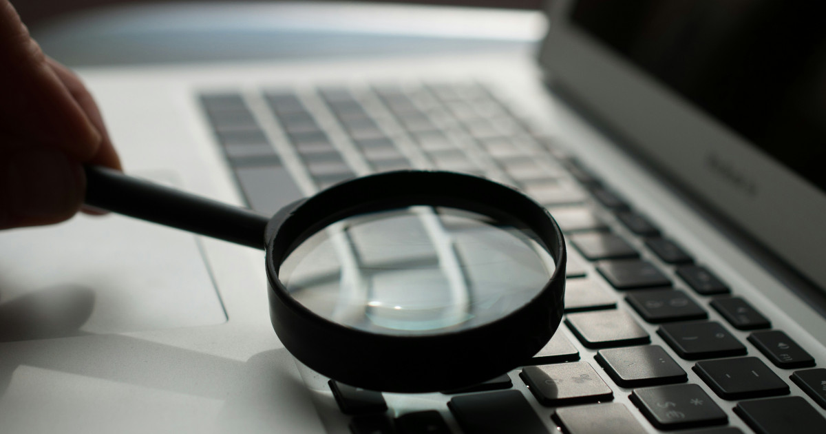 Decorative photo of a magnifying glass on a laptop keyboard.
